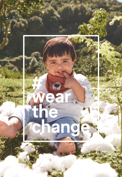 Infant in a field wears high-quality baby clothes made of sustainable cotton